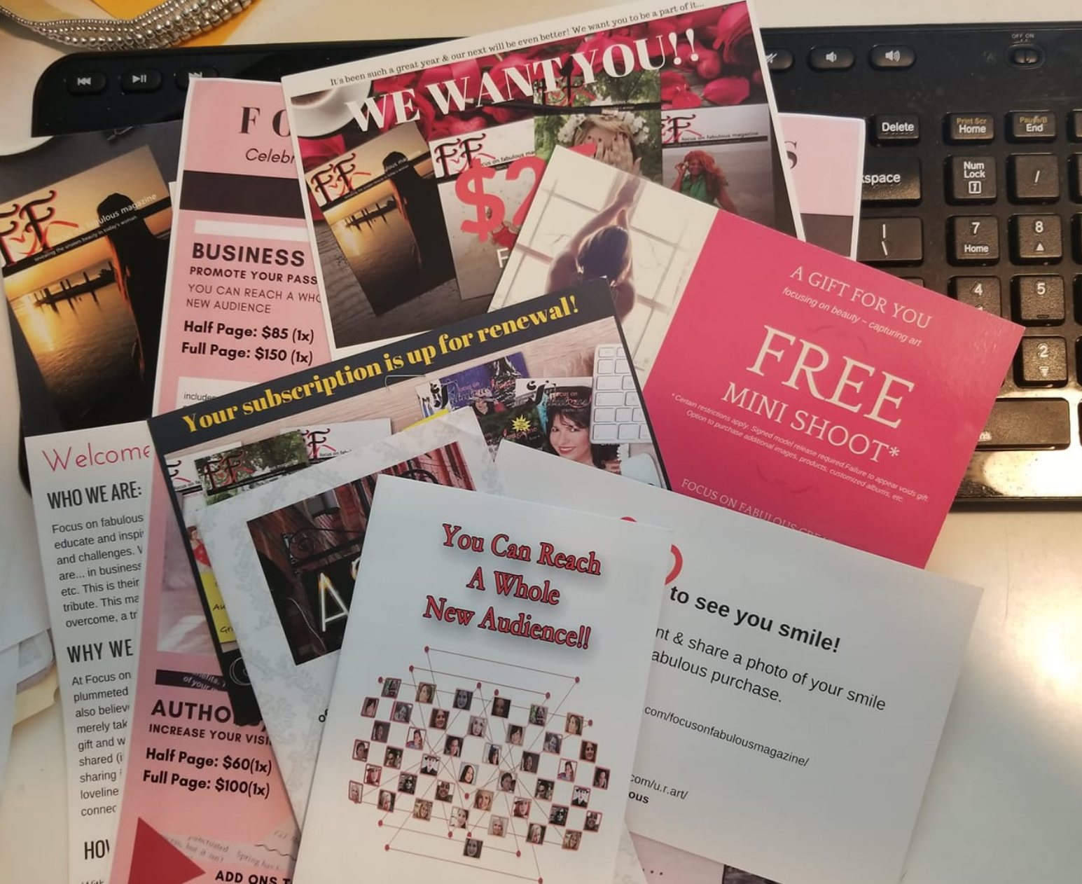 Printed Focus on Fabulous marketing flyers, brochures and cards fanned out over a black computer keyboard